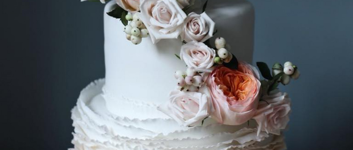 Signature ruffle wedding cake with fresh floral arrangement