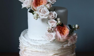 Signature ruffle wedding cake with fresh floral arrangement