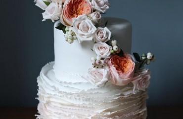 Signature ruffle wedding cake with fresh floral arrangement