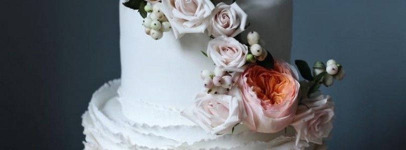 Signature ruffle wedding cake with fresh floral arrangement